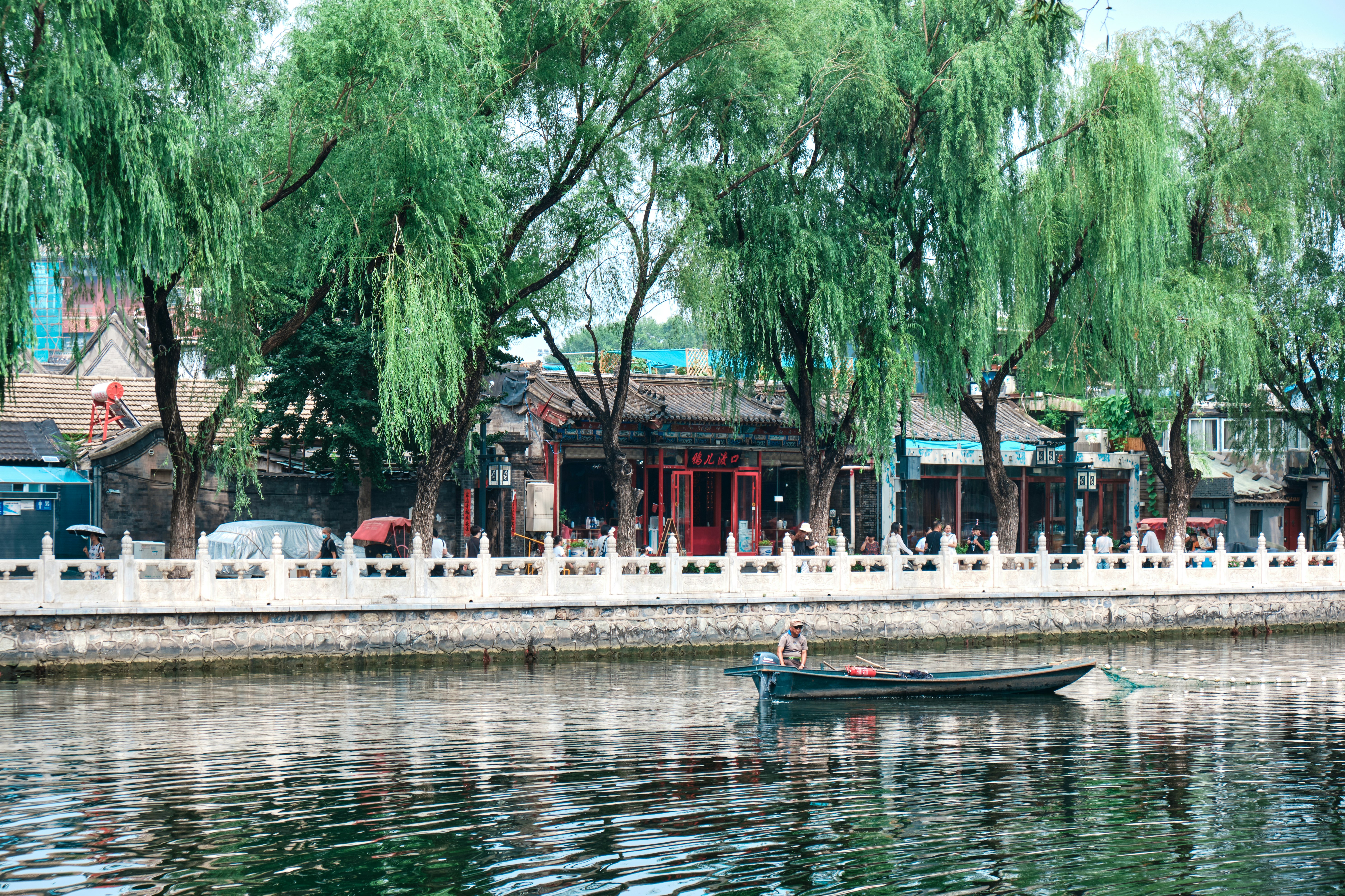 people riding on boat on river near trees and building during daytime